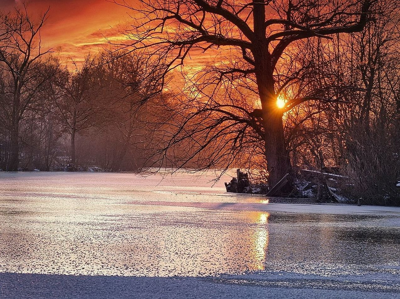 Sol bajo iluminando el hielo agrietado del lago